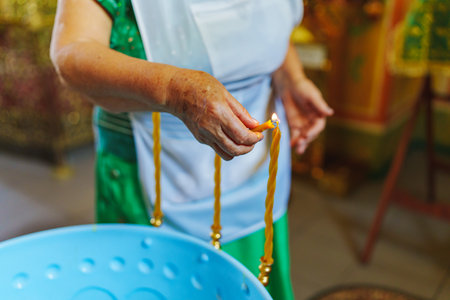 Woman lighting candles on a Baptismal font in the Orthodox Church.の写真素材
