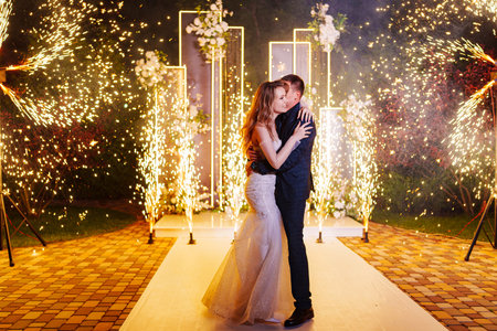 The bride and groom on the wedding ceremony venue with fireworks at night .の写真素材