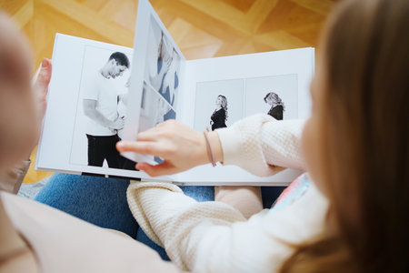 mother and daughter flips through a book with photos of dad and pregnant mom.の写真素材