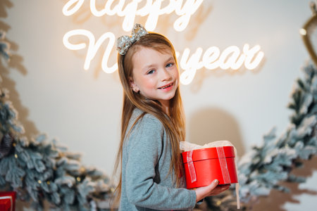 Cute little girl with red gift box in christmas decor.の写真素材