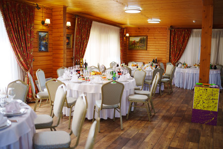 Tables set for the party in the wooden ballroom in the chalet.のeditorial素材