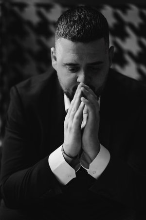 A serious, thoughtful man with hands to the face in a business suit is sitting. The concept of modern style of business people.の写真素材