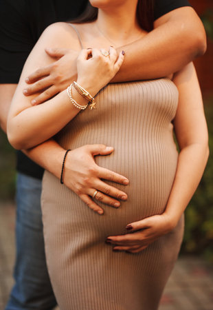Pregnant woman in a knitted dress holding her belly