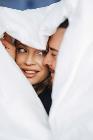 A man and a woman under the blanket on a bed.の写真素材