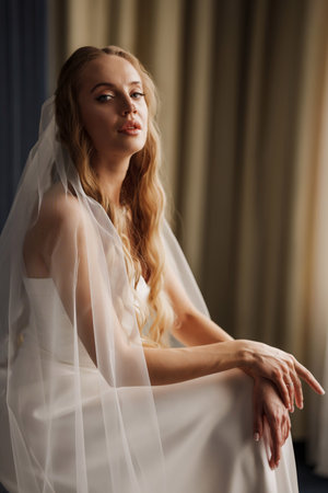 The bride in simple beautiful elegant wedding dress sitting on a chairの写真素材