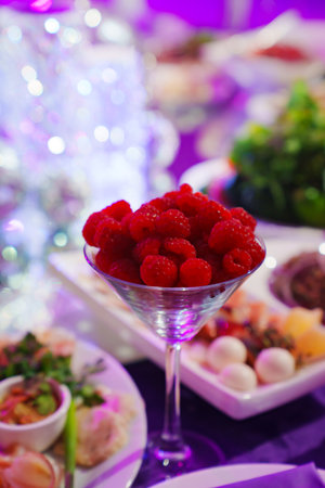 A glass of bowl with fresh raspberries on the served table.の写真素材