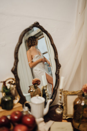 in the mirror of a young woman with blonde hair in a white dressの写真素材