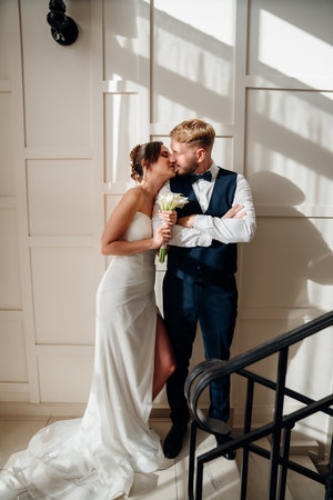 Portrait of a beautiful groom and a bride against the white wallの写真素材