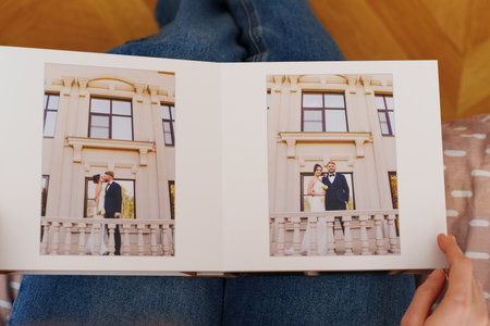 Female hands flipping through a photo book with wedding photosの写真素材