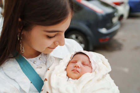 Newborn baby in the arms of his sister in a white dressの写真素材