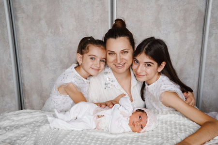 Happy mother with a newborn and older daughters.の写真素材