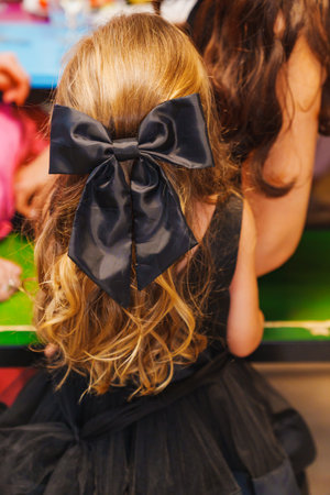 A beautiful bow made of black silk ribbon on the hair of a little girl.の写真素材