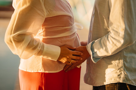 A man holds on to the tummy of a pregnant woman with his hands.の写真素材