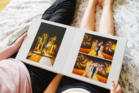 Mom and daughter flipping through a wedding photo book on the bed.の写真素材