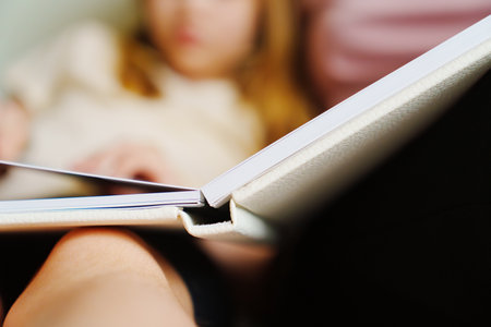 Mother and daughter flip through the pages of a photo book in a white binding.の写真素材