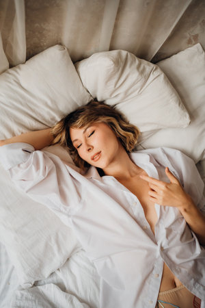 woman in white shirt in bed. female attractiveness and sexuality. A romantic morning.の写真素材