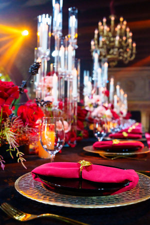 Beautiful festive table setting with fresh red flowers, napkins and candles. Evening romantic...