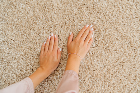 close-up a woman's hand touching the beige Interior pile carpet made of polypropylene. Long fibers form a high pile. pleasant lint texture, softness and hypoallergenicity.の写真素材