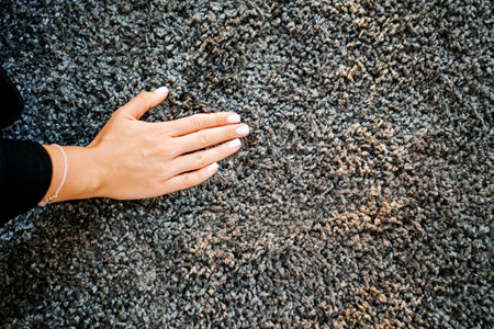 close-up a woman's hand touching the gray Interior pile carpet. Long fibers form a high pile....