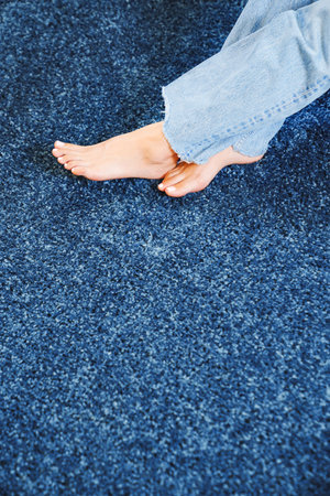 close-up bare feet on the blue Interior pile carpet. Long fibers form a high pile. pleasant lint texture, softness and hypoallergenicity.の写真素材