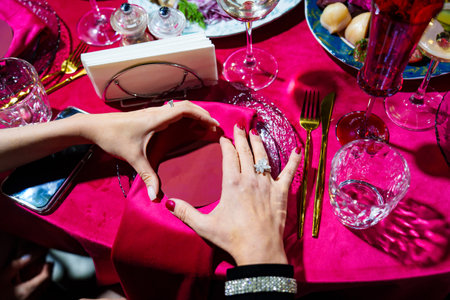female hands. Setting a festive table with a red tablecloth and napkins with a name card. Professional decorator for the holiday.の写真素材