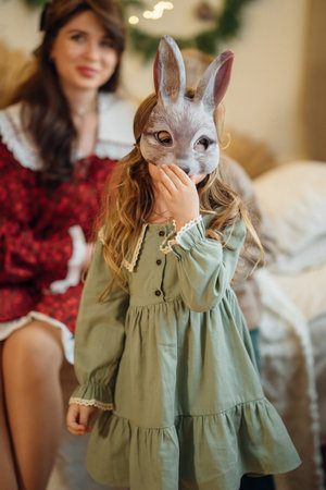 Little girl in a green dress and a carnival hare mask. The tradition of dressing up for the New Year. Festive masquerade.の写真素材