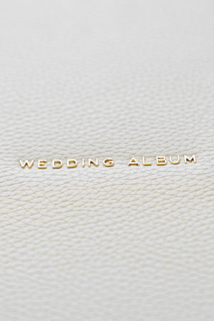 The inscription Wedding Album in gold letters on the white leather cover of bookの写真素材
