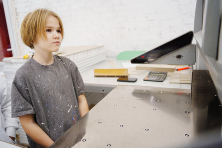teen girl looking at the professional paper cutter in a printing house