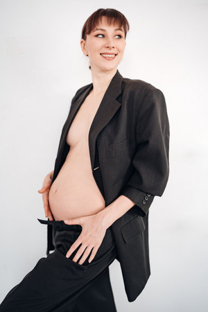 Young pregnant woman wearing oversized suit jacket and posing confidentlyの写真素材