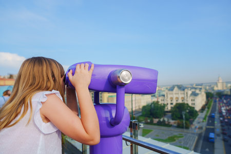 a teenage girl looks into the Binoscope from the observation deck at a height.の写真素材