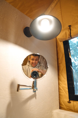 Lamp and round mirror in the bathroom in the tent house in the glamping. A solution for the interior of a campsite. reflection of a male photographer.の写真素材