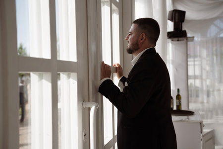 The groom in a black suit by the windowの写真素材