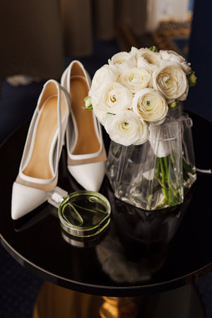 A stylish wedding. bridal bouquet, perfume and shoes on the table.の写真素材