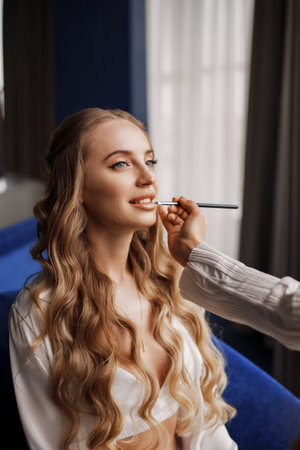 makeup artist makes makeup for a beautiful blonde with long hair.の写真素材
