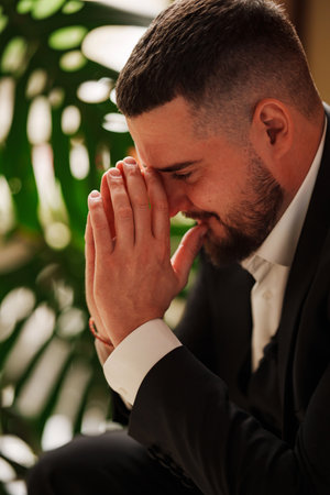 A serious, thoughtful man with hands to the face in a business suit is sittingの写真素材