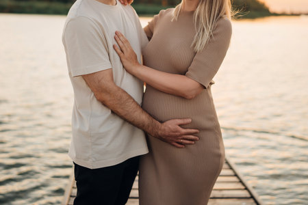 without faces. A man gently hugs a pregnant woman on the pier. Travel and sea cruises during pregnancy. A healthy and happy family.の写真素材