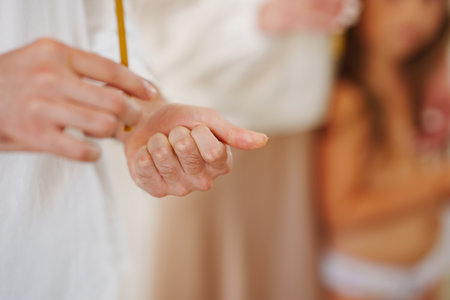 A man clutches a piece of wax in his hand with hair cut from a child at a baptism. Orthodox...