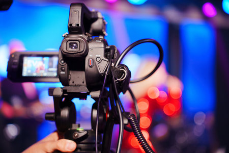 A professional videographer is filming a concert on stage. blurred artists on stage, focus on the...