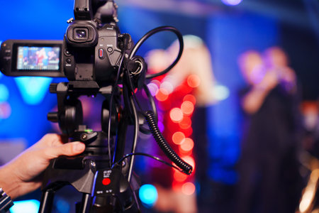 A professional videographer is filming a concert on stage. blurred artists on stage, focus on the...