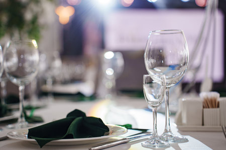 Setting the festive table. empty wine glasses and plates with green napkins. cutlery for the...
