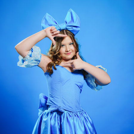 Cute teenage girl in blue doll dress with big blue bow posing.の写真素材