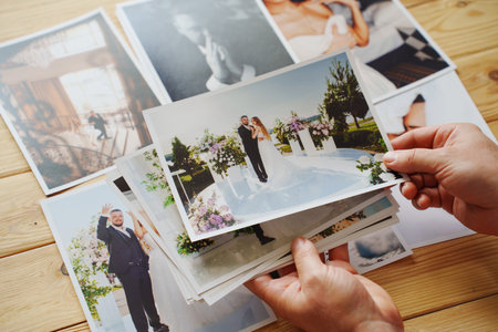 Mens hands put on the wooden table and show wedding photos.