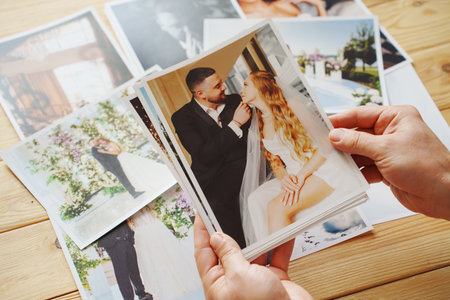 Mens hands put on the wooden table and show wedding photos.