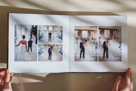 Female hands flipping through a photo book with wedding photos on a white tableの写真素材