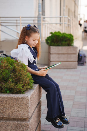 Young girl wearing a stylish outfit and reading on a sunny day outdoorsの写真素材