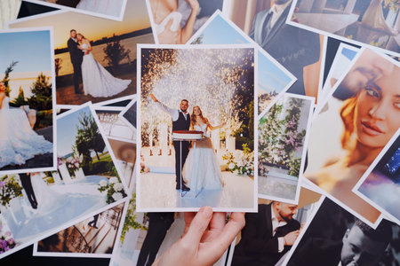 womens hands put on the table and show wedding photos.の写真素材
