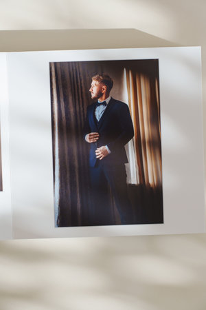 page of an open photo book with wedding photos on a white table