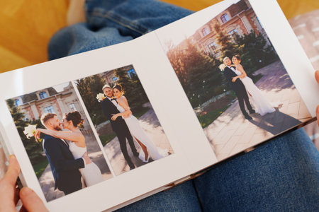 Female hands flipping through a photo book with wedding photosの写真素材