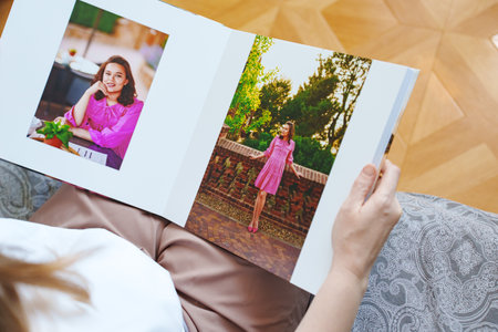 woman is holding and flipping through a photo book with a pregnancy photo shoot