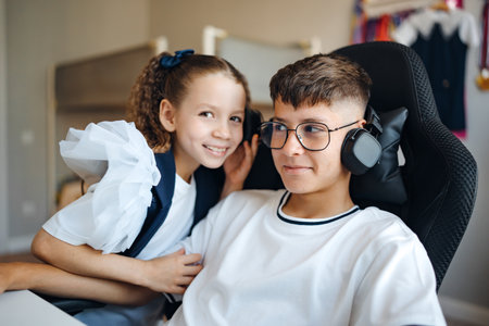 Siblings enjoying time together while listening to music in a cozy roomの写真素材